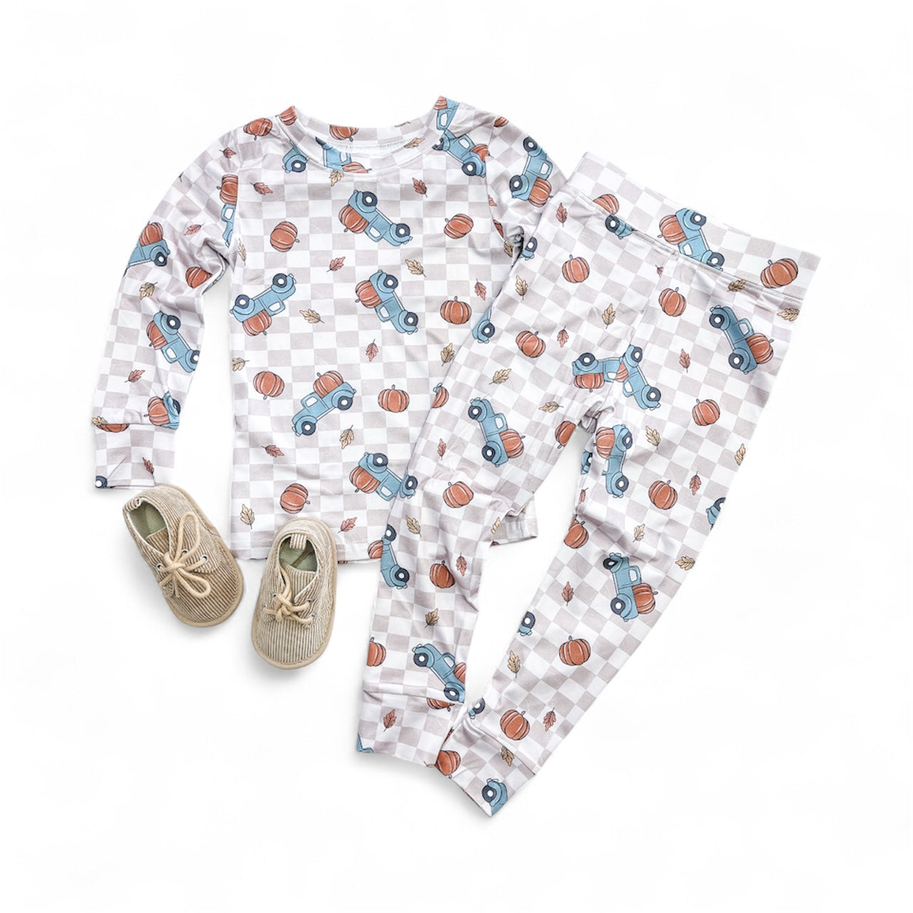 The Fall Farm Run Jammies Set by Tiny Tot Bundles features checkered children’s pajamas with blue cars and basketballs, shown with beige woven baby shoes against a white background.