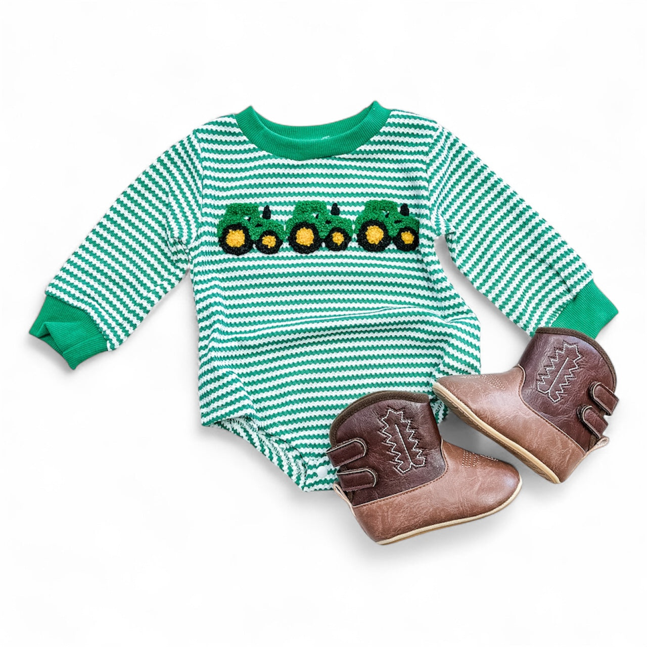The Tiny Tot Bundles Green Tractor Long Sleeve Bubble features green and white stripes with yellow and green tractor designs, paired with small brown cowboy boots, shown on a white background.