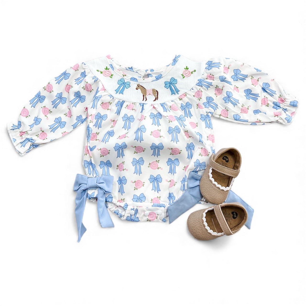 The Derby Darlin Bubble by Tiny Tot Bundles is a white long-sleeve onesie with blue bows, pink flowers, side bows, horse embroidery on the chest, and paired with brown scalloped-edge baby shoes.