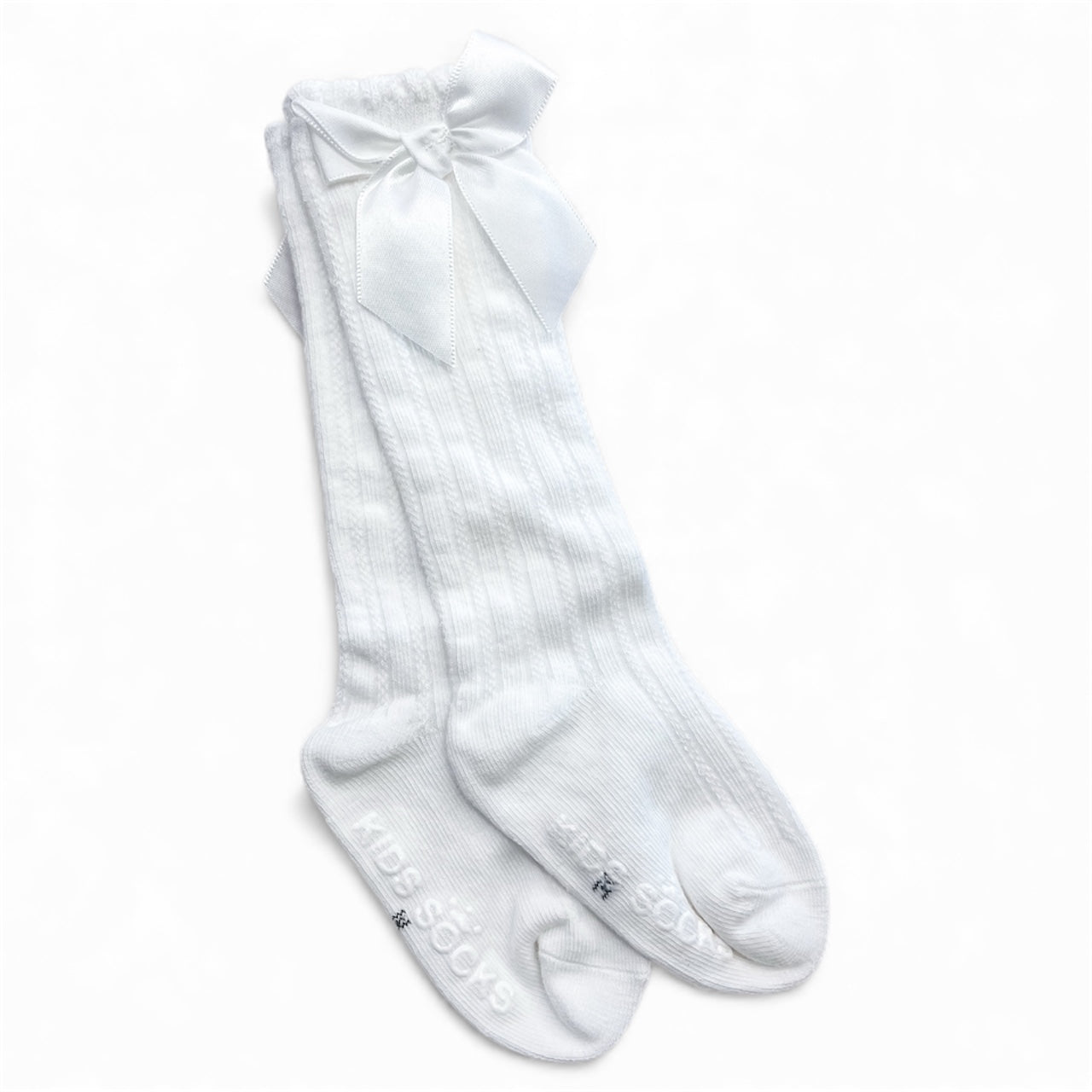Tiny Tot Bundles Pretty Bow Ribbed Socks: white knee-high kids socks with ribbed texture, a large bow on top, and "KIDS SOCKS" printed on the soles, shown on a plain white background.