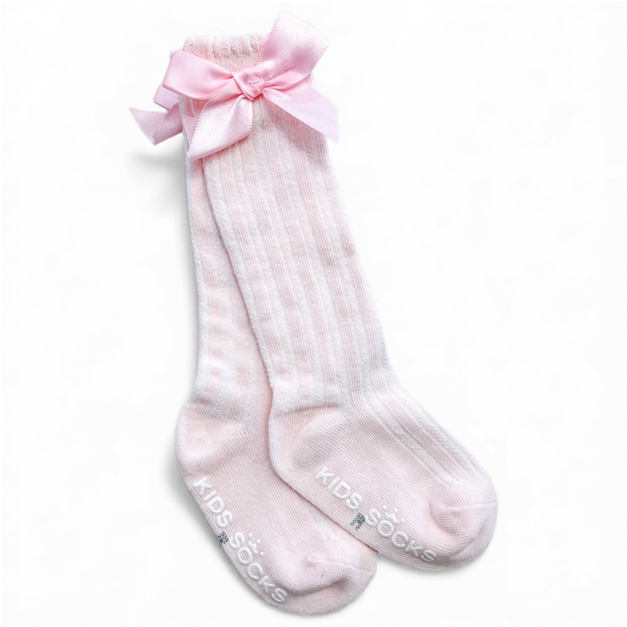 Pretty Bow Ribbed Socks by Tiny Tot Bundles: Light pink, ribbed knee-high kids’ socks with large pink satin bows on the cuffs and “KIDS SOCKS” printed in white on the soles.