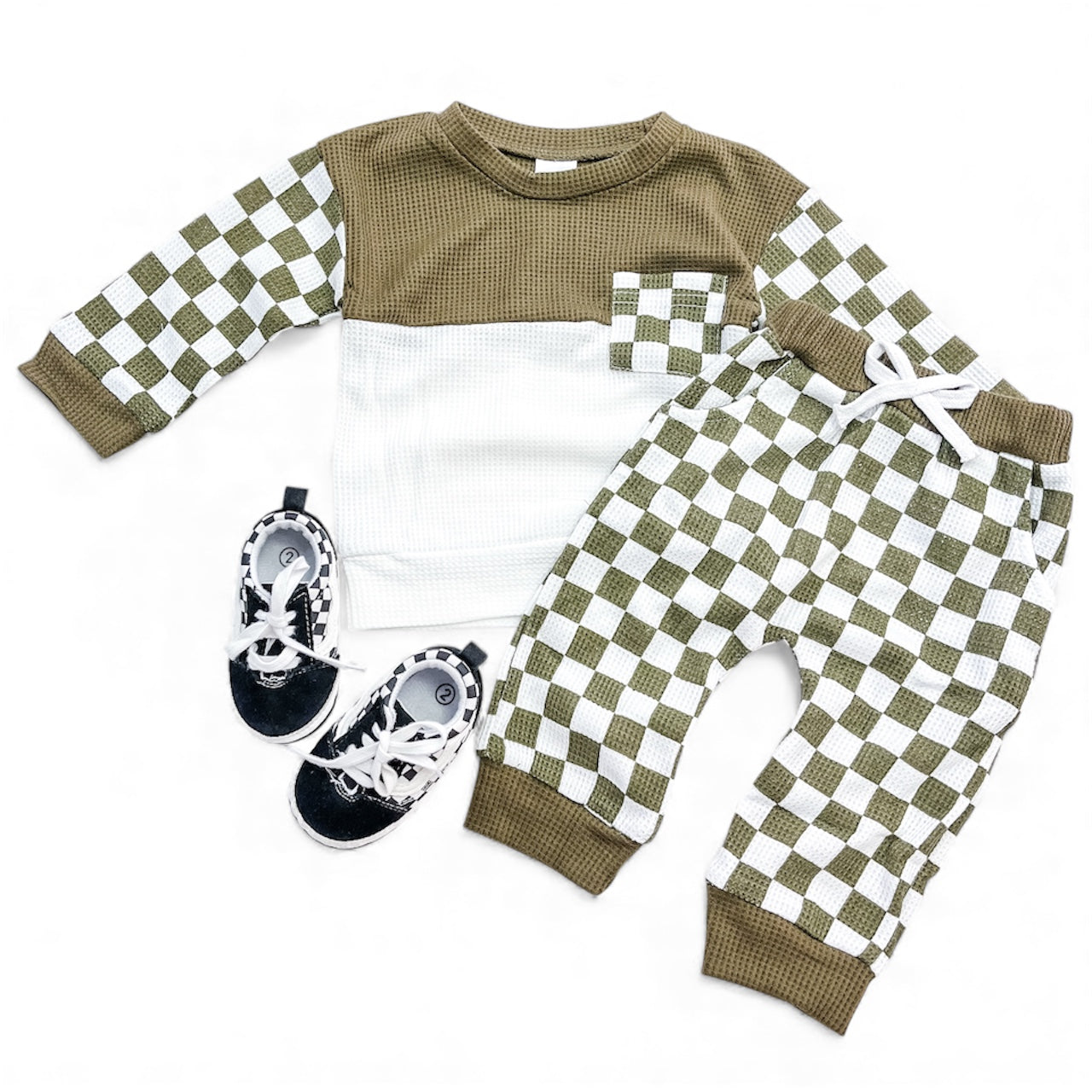 The Tiny Tot Bundles Cozy Checkerboard Set includes a long-sleeve olive and white checkered top with a pocket, matching jogger pants, and black shoes with white laces, all displayed on a white background.