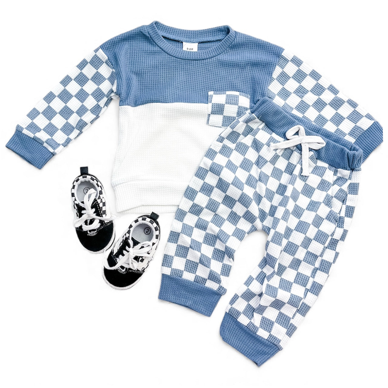 The Cozy Checkerboard Set by Tiny Tot Bundles features a blue and white checkered long-sleeve top with chest pocket, matching pants with white drawstring, and comes with black and white sneakers placed beside the outfit.