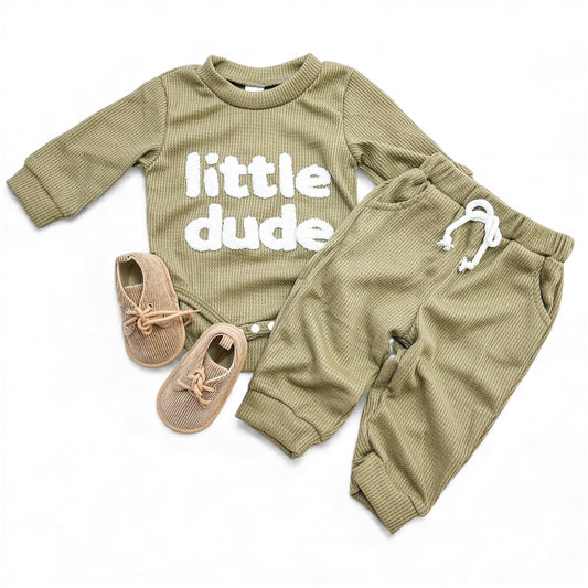 The Tiny Tot Bundles Little Dude Waffle Set features a green ribbed long-sleeve top with "little dude" in white, matching pants with a white drawstring, and light brown baby shoes with bows, displayed on a white background.