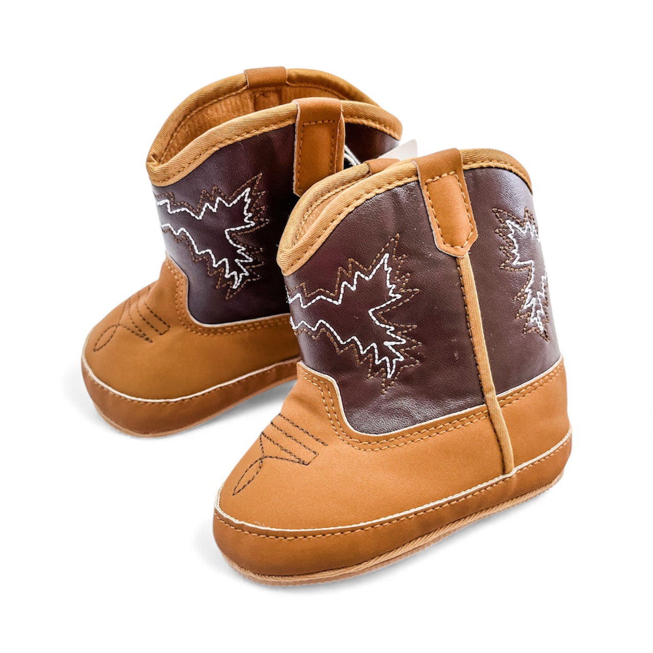 Tiny Tot Bundles' Infant Rodeo Boots feature brown and tan colors, white leaf-pattern stitching on the sides, and soft soles, shown against a white background.