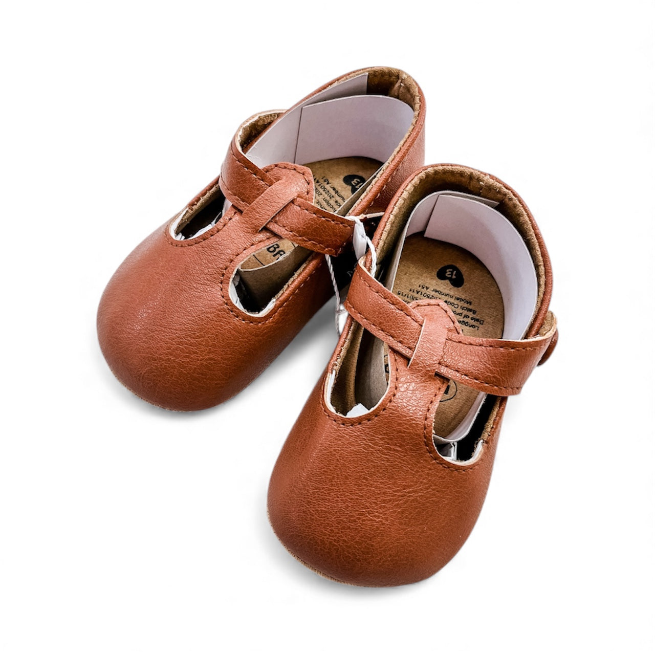 Tiny Tot Bundles' Tiny Wanderer Infant Flats are brown leather baby shoes with T-bar straps, buckles, soft soles, and simple edge stitching, shown on a white background.