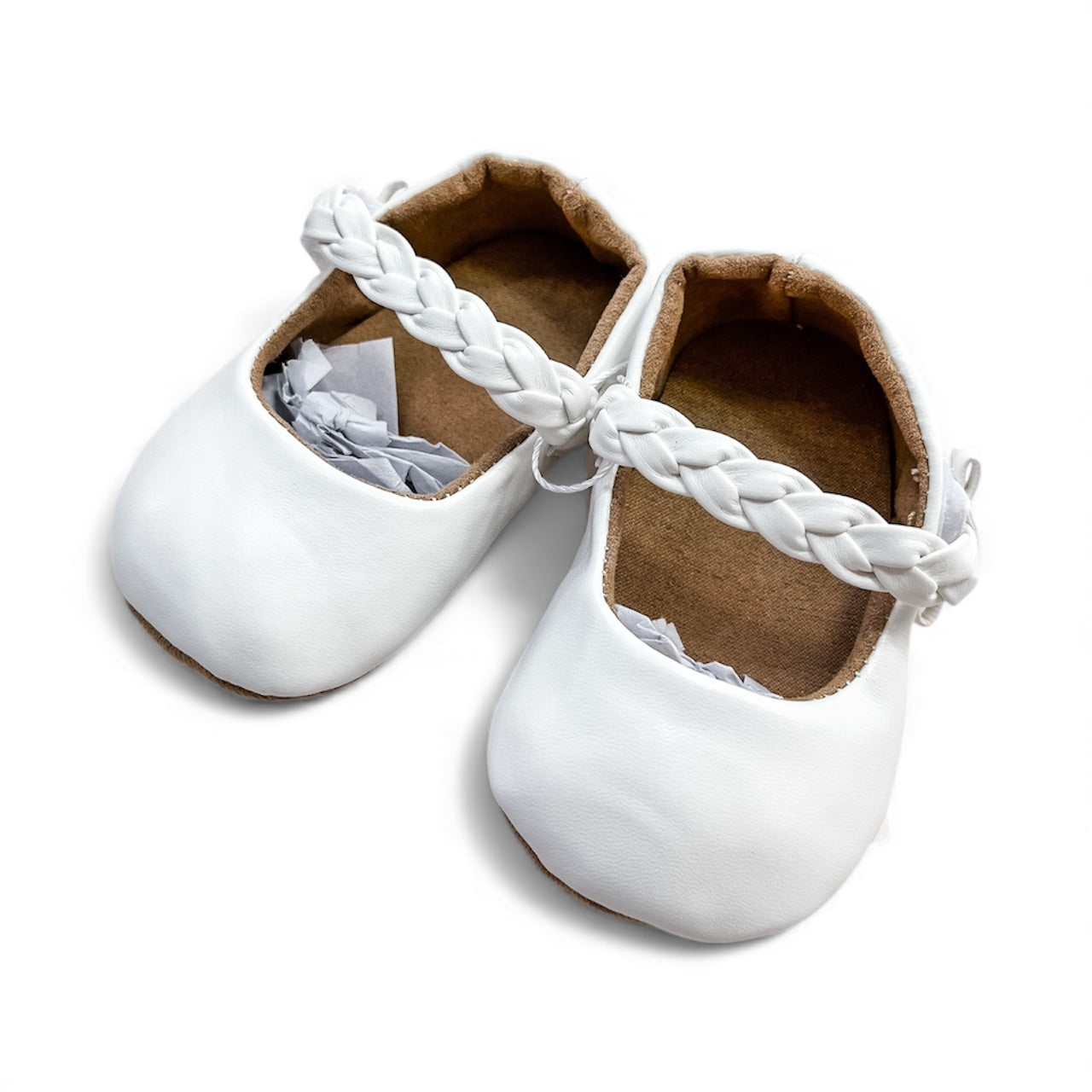 A pair of Braided Baby Mary Janes by Tiny Tot Bundles, in white with braided straps and a soft brown inner lining, displayed on a white background with paper stuffing inside.