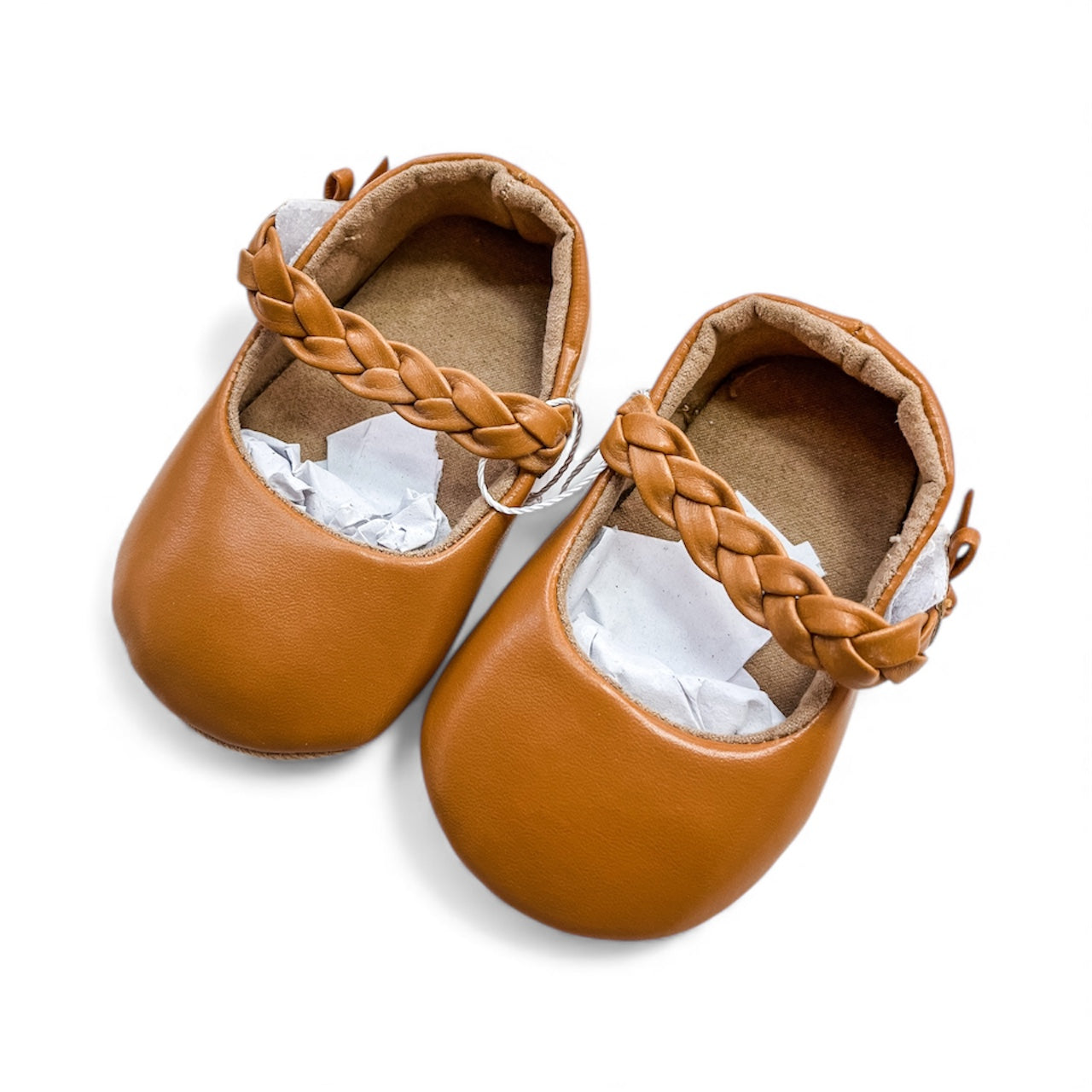 Tiny Tot Bundles Braided Baby Mary Janes are small, brown baby shoes with braided straps, a round toe design, and a soft inner lining. Shown on a white background with white tissue paper inside.