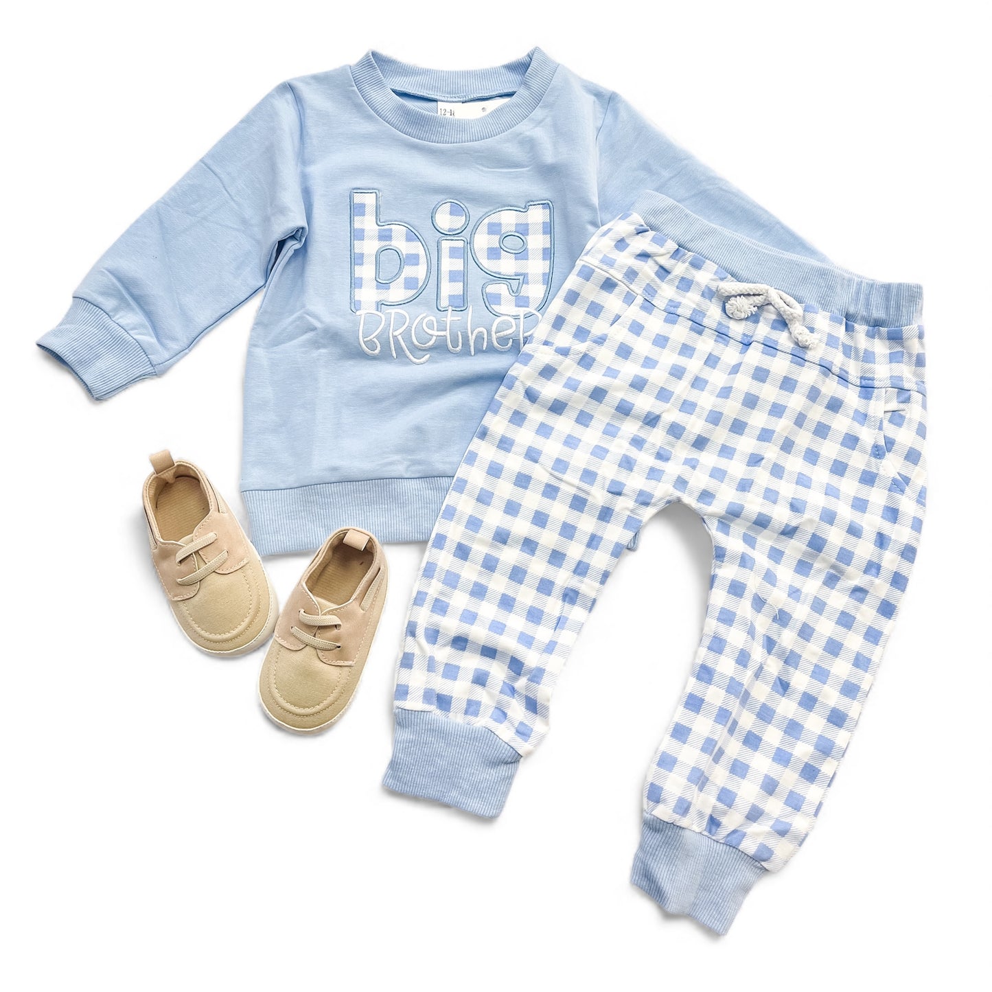 The Tiny Tot Bundles Big Brother Gingham Set, featuring a light blue "Big Brother" sweatshirt and blue-white checkered drawstring pants, is paired with beige baby shoes and displayed flat on a white background.