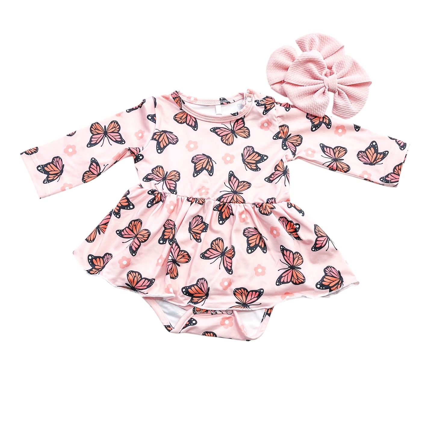 The Little Flutter Longsleeve Twirl Romper by Tiny Tot Bundles is a pink baby dress with butterfly and flower prints, an attached bodysuit, and comes with a large matching pink fabric bow headband.