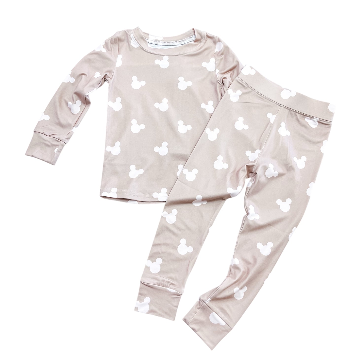 The Cozy Mouse Jammies Set by Tiny Tot Bundles features a light beige long-sleeve top and pants with white Mickey Mouse head prints, displayed flat on a white background.