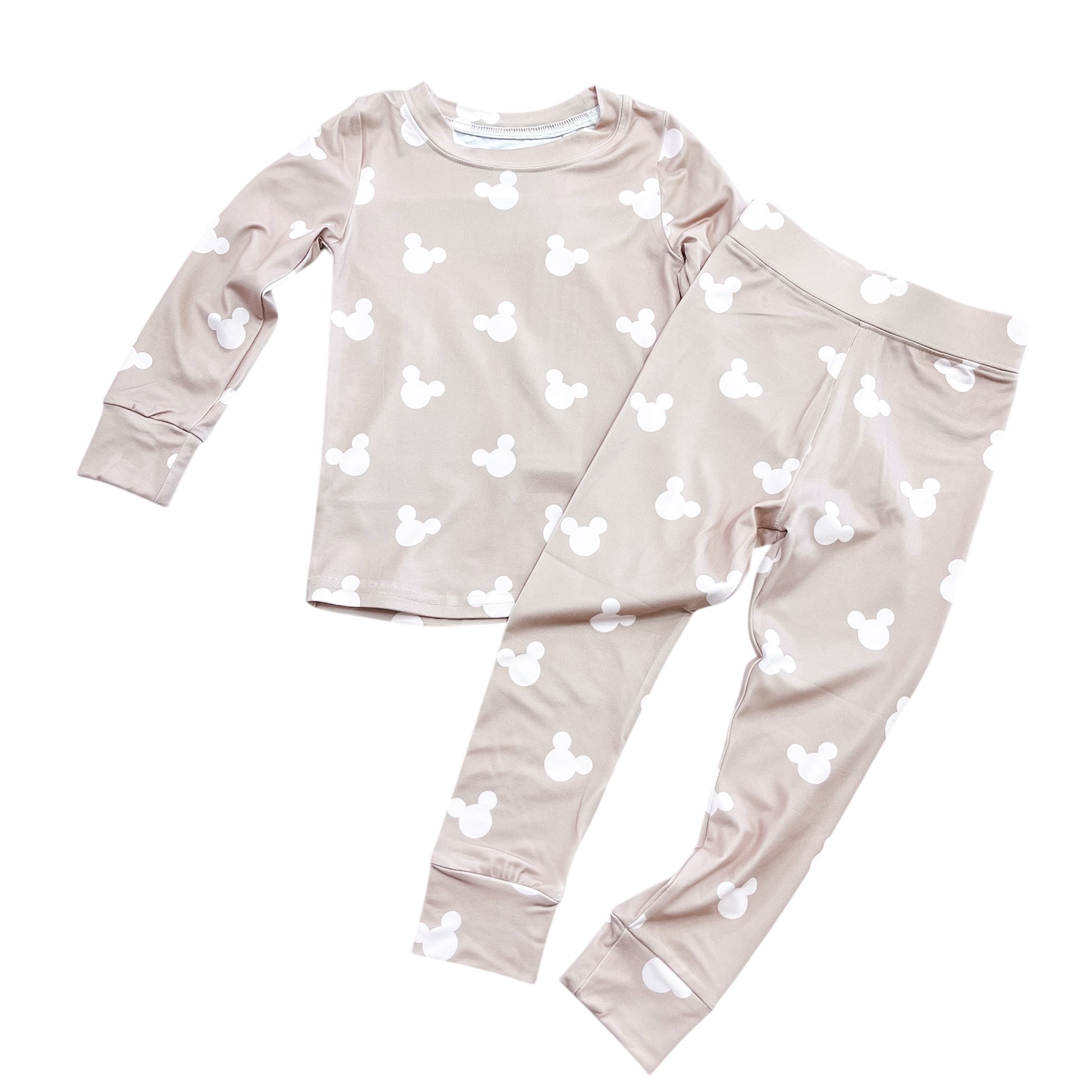 The Cozy Mouse Jammies Set by Tiny Tot Bundles features a light beige long-sleeve top and pants with white Mickey Mouse head prints, displayed flat on a white background.