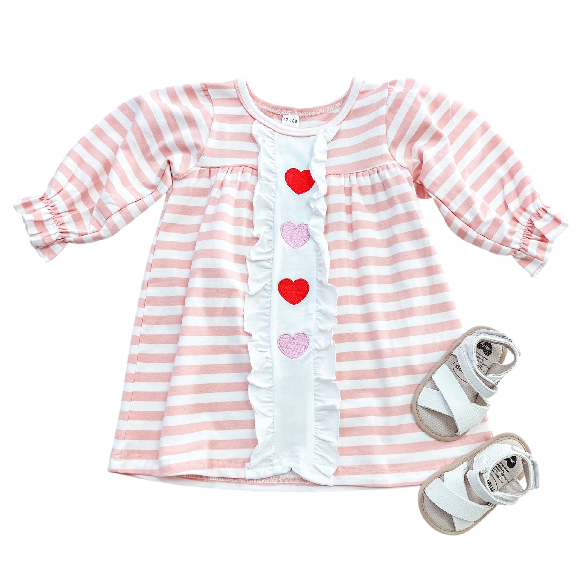 The Rosy Ruffle Hearts Dress by Tiny Tot Bundles features pink and white stripes, ruffled trim, and three heart appliqués, paired with white and beige baby sandals.