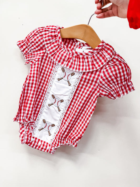 The Home Run Gingham Bubble by Tiny Tot Bundles is a red and white gingham baby romper with short sleeves, a rounded collar, and embroidered tennis rackets on a white front panel, displayed on a wooden hanger.