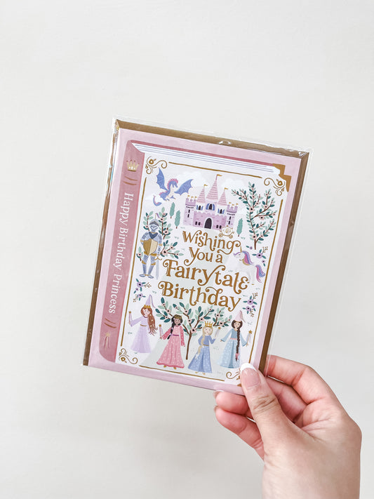 A hand holds the "Fairytale Princess - Birthday Card" by love Light Paper, featuring princesses, a castle, and "Wishing You a Fairy Tale Birthday" on the front; "Happy Birthday, Princess!" appears in gold on the side.