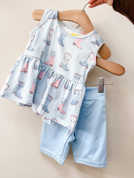 A hand holds the Cowgirl Stripe Peplum Set by Tiny Tot Bundles: a sleeveless blue and white striped top with pink and blue rain boots print, paired with light blue shorts.