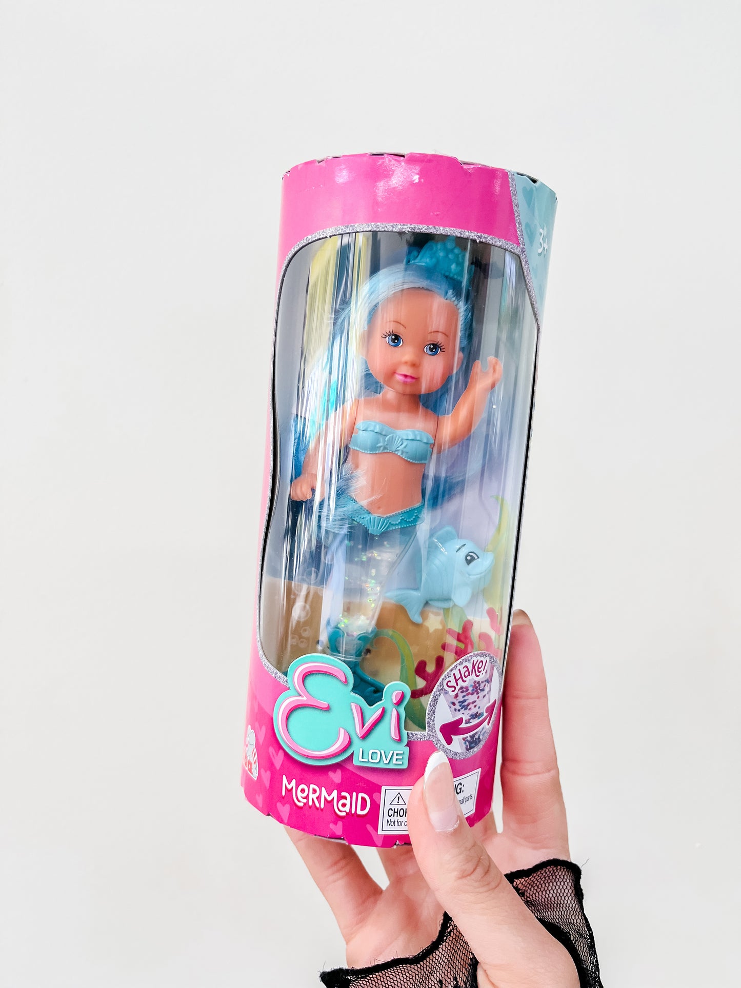 A hand holds a packaged Toy Smith Evi Love Mermaid Doll featuring blue hair, a blue mermaid outfit, and a dolphin accessory against a plain white background.
