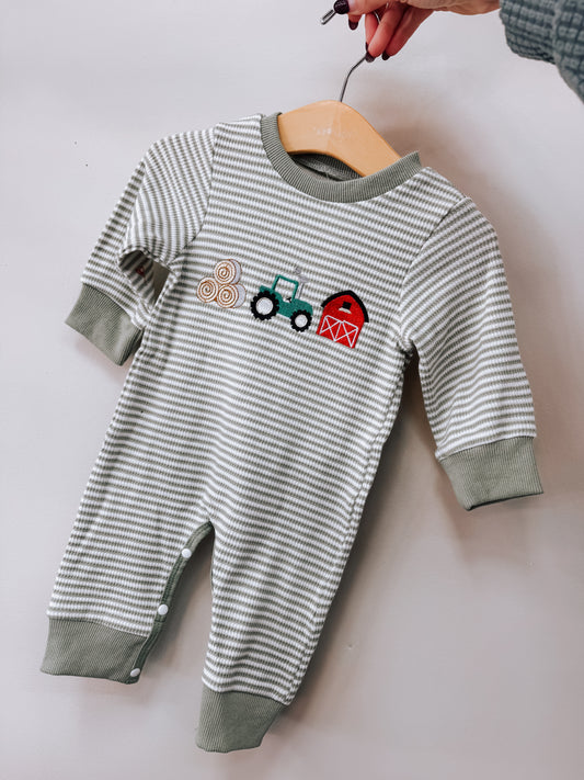 Tiny Tot Bundles Farm Friends Long Sleeve Romper with thin gray and white stripes, featuring an embroidered design of hay bales, a tractor, and a red barn on the chest.