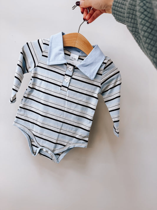 Tiny Tot Bundles Blue Striped Polo Romper featuring blue, black, and white horizontal stripes, a solid light blue collar, and a three-button placket.