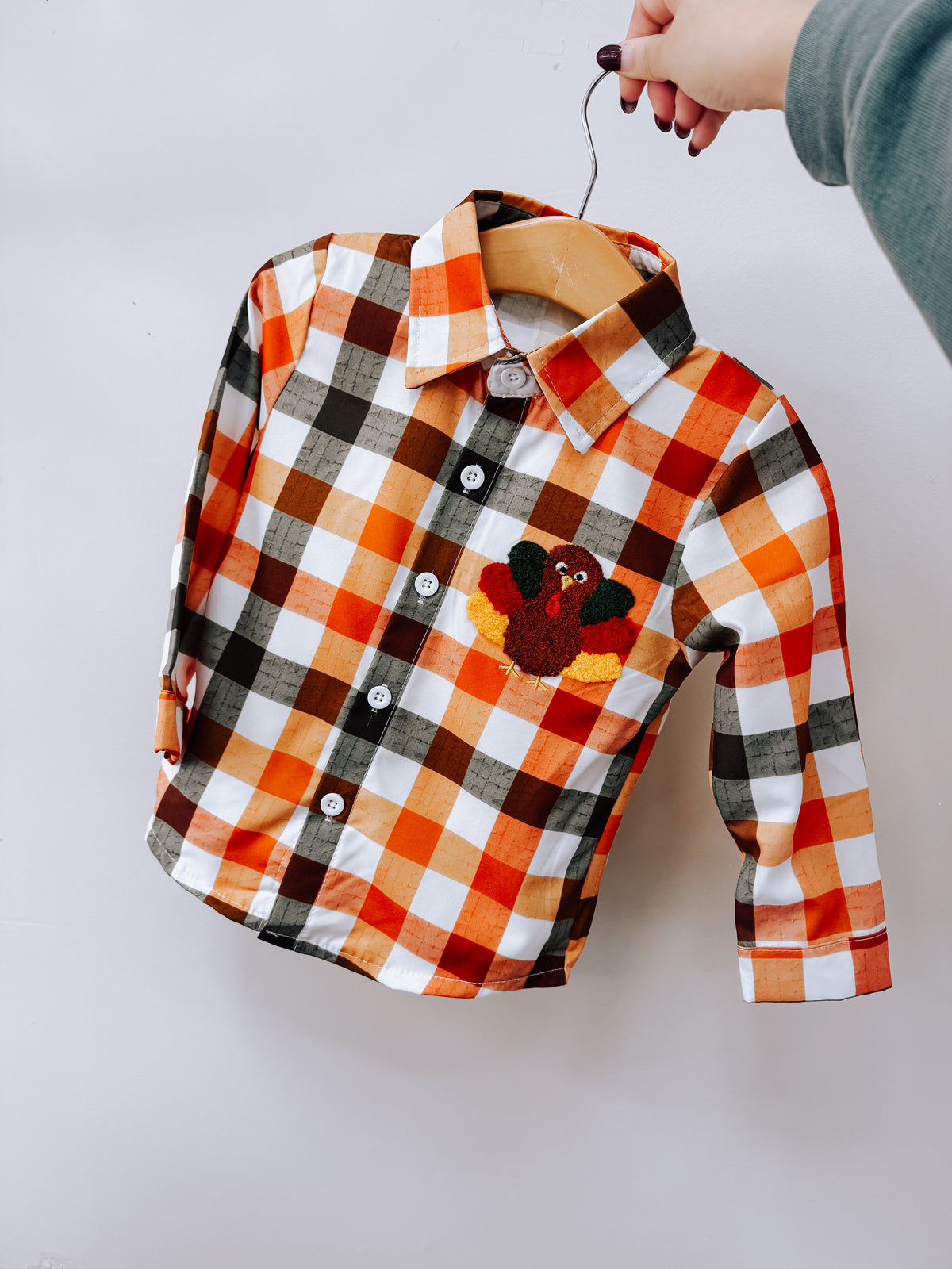 Tiny Tot Bundles Fall Plaid Turkey Shirt featuring a long-sleeved button-down design in an orange, white, and black plaid pattern with a small turkey patch on the chest.