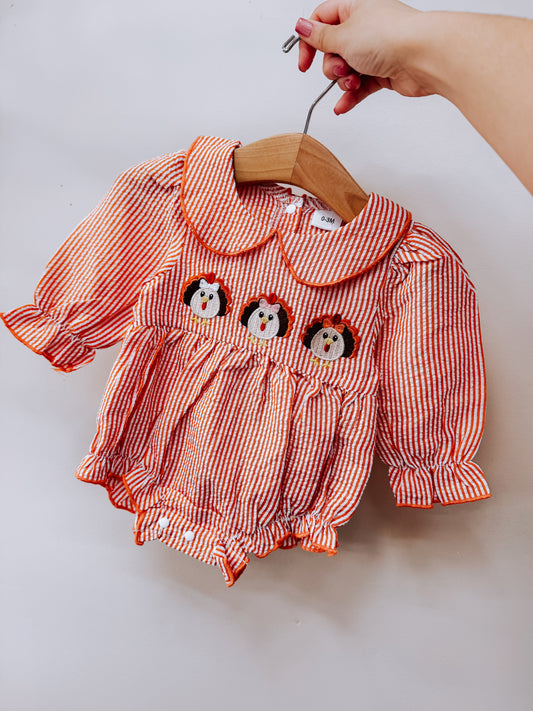 Tiny Tot Bundles Gobble Smocked Stripe Romper featuring orange and white stripes, a Peter Pan collar, and three turkey appliqués across the chest.