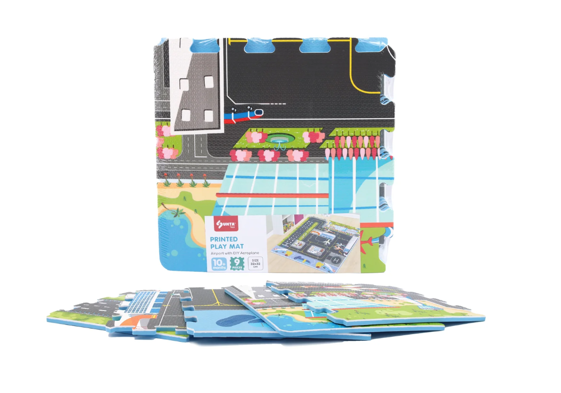 The Triaction Plane & Airport Play Mat features colorful interlocking foam tiles with a plane and airport design, arranged upright with extra tiles in front and packaging displayed in the center.