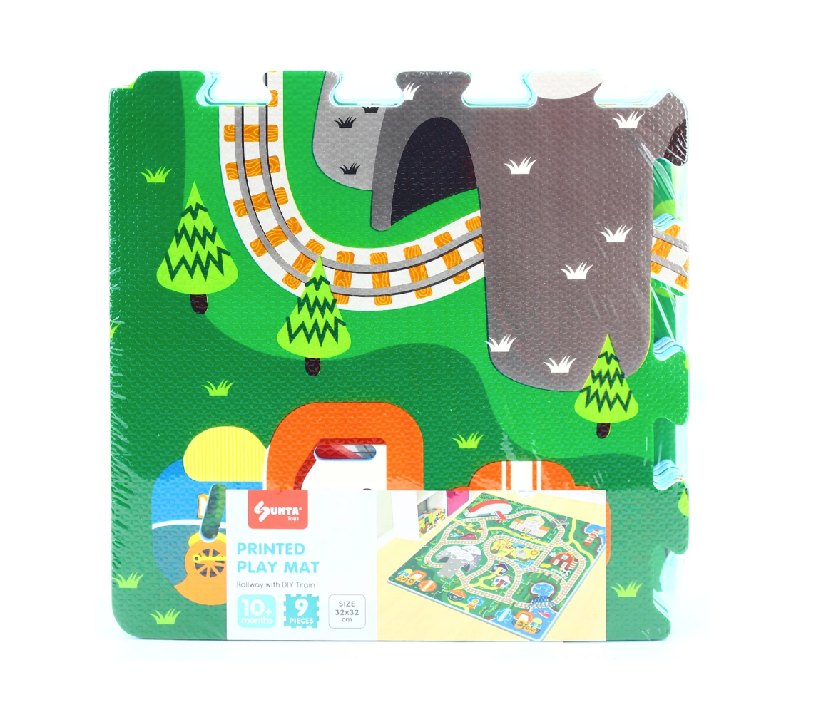 The Triaction Train & Track Play Mat is a colorful foam puzzle mat with roads, train tracks, trees, and mountains. The packaging reads “Train & Track Play Mat” and shows the suitable age, features, and a sample image.