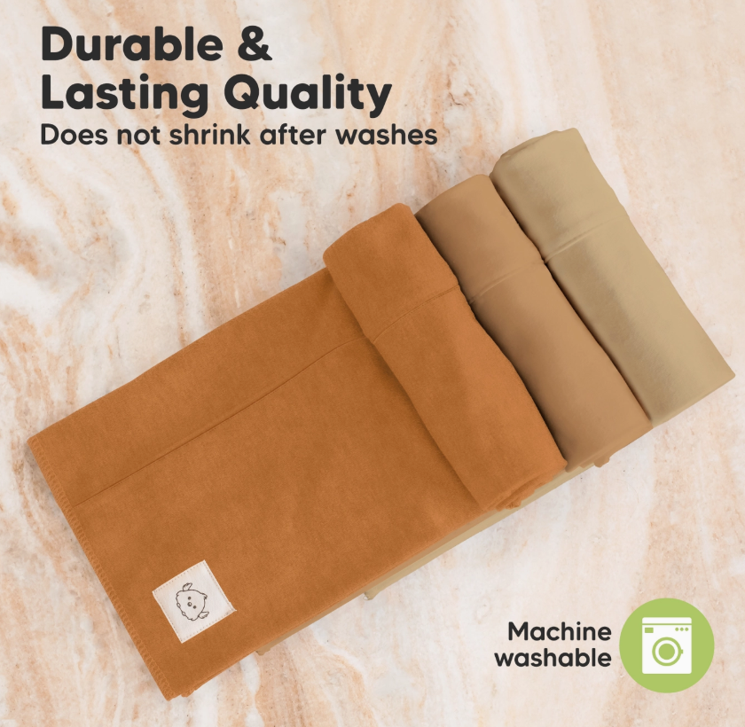 Six keababies Shea Burp Cloths in terracotta tones are neatly arranged on a marble surface. Text reads, Durable & Lasting Quality—won’t shrink after washing. A green machine washable icon is displayed.