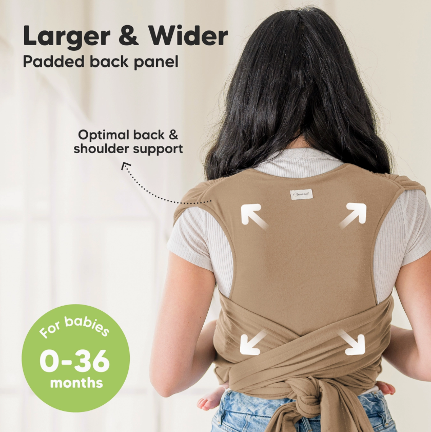 A woman with long dark hair wears the keababies Baby Wrap Carrier - Warm Hearth, featuring a larger and wider padded back panel for enhanced back and shoulder support. For babies 0-36 months. White arrows highlight key support areas.