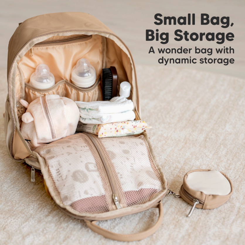 The keababies Diaper Bag Backpack, Baby Bag with Changing Pad, is open to reveal organized compartments for bottles, diapers, wipes, a brush, and a small pouch. Text reads: Small Bag, Big Storage—a wonder bag with dynamic storage.