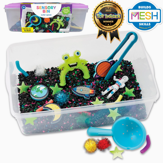 The Creativity For Kids Sensory Bin - Outer Space includes black rice, colorful space-themed toys (green monster, astronaut, planets, stars), blue scooping tools, and comes in packaging displaying award badges.