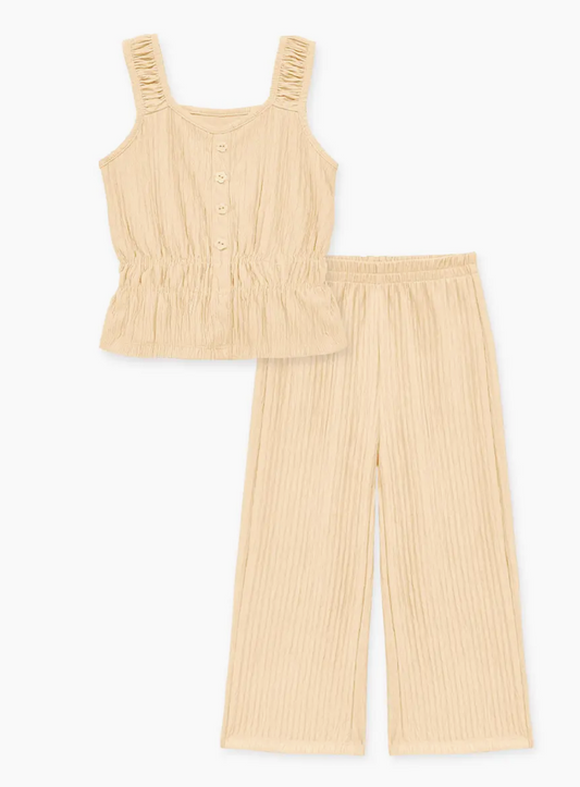 The Ivory Satin Set from Cutie Patootie features a sleeveless beige top with buttons and an elastic waist, paired with matching wide-leg, elastic-waist pants in a crinkled, textured fabric.