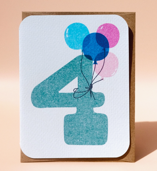 The 4th Birthday Card from Paper Chain Studios features a large turquoise number 4 with three balloons—two blue, one pink—tied together, displayed against a light peach background.
