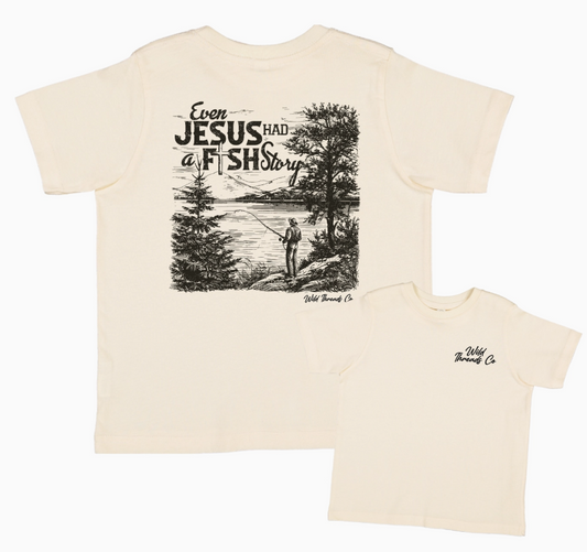 The Fish Story T-Shirt by Wild Threads Co is cream-colored, featuring a back graphic of a man fishing with the phrase “Even Jesus had a fish story,” and a small Wild Threads Co logo on the front left chest.