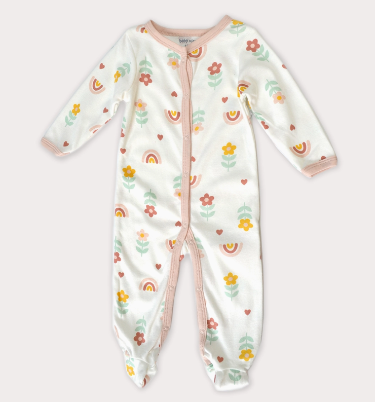 The Lollipop Dreams Sunny Sprouts Zip Footie is a white baby onesie with long sleeves, covered feet, pink trim, and a colorful floral, rainbow, and heart print. It features a convenient zip closure down the front and legs.