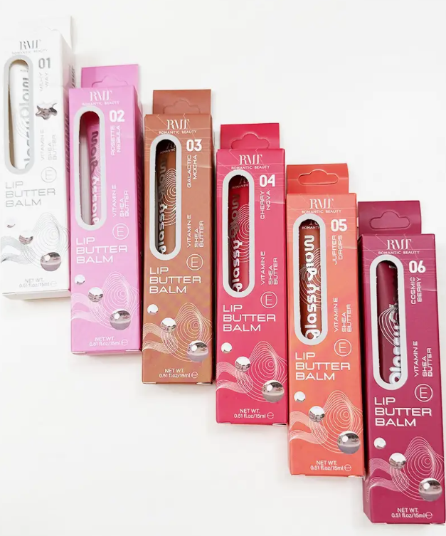 Six boxes of love & repeat Vitamin E Lip Butter Balm are lined up by color—white, pink, peach, orange, red, and berry. Each box features a vertical window displaying the lip balm tube inside.
