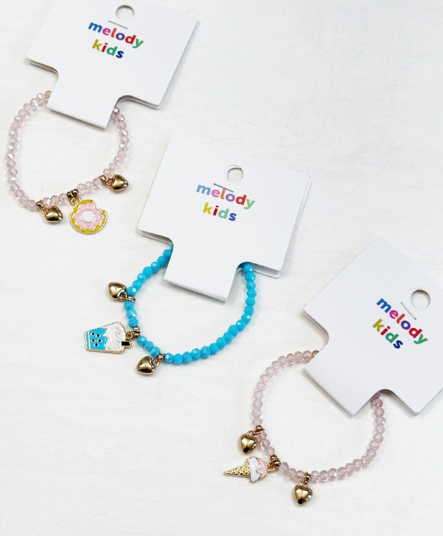 The love & repeat Sweet Treat Charm Bracelets set includes three beaded bracelets: one with pink beads and a donut charm, one with blue beads and a milk carton charm, and one with pink beads and an ice cream cone charm.