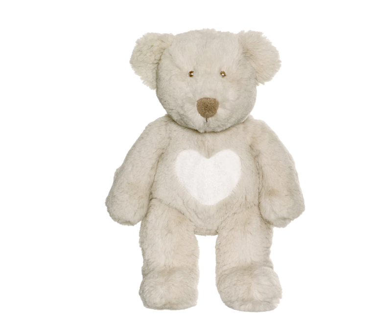 The Triaction Teddy Cream Heart Plush is a beige teddy bear with a white heart on its chest, shown sitting upright against a plain white background.
