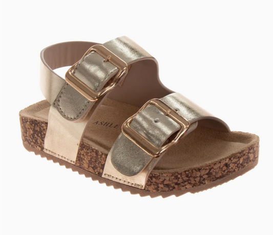 The Golden Sunshine Sandals by Josmo Shoes Inc feature two wide gold metallic straps with large gold buckles and a cork-textured platform sole with a ridged bottom.