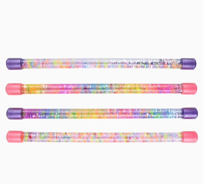 Four The Toy Network Glitter Water Batons, filled with colorful glitter and confetti and capped in pink or purple, are lined up horizontally on a white background.