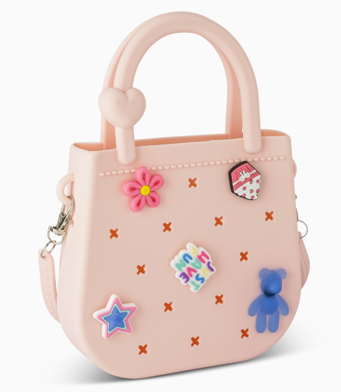The Mini Round Eva Purse - Pink by core home features two handles, colorful charms (flower, blue bear, star, heart), small orange x patterns, and a heart detail on one handle.