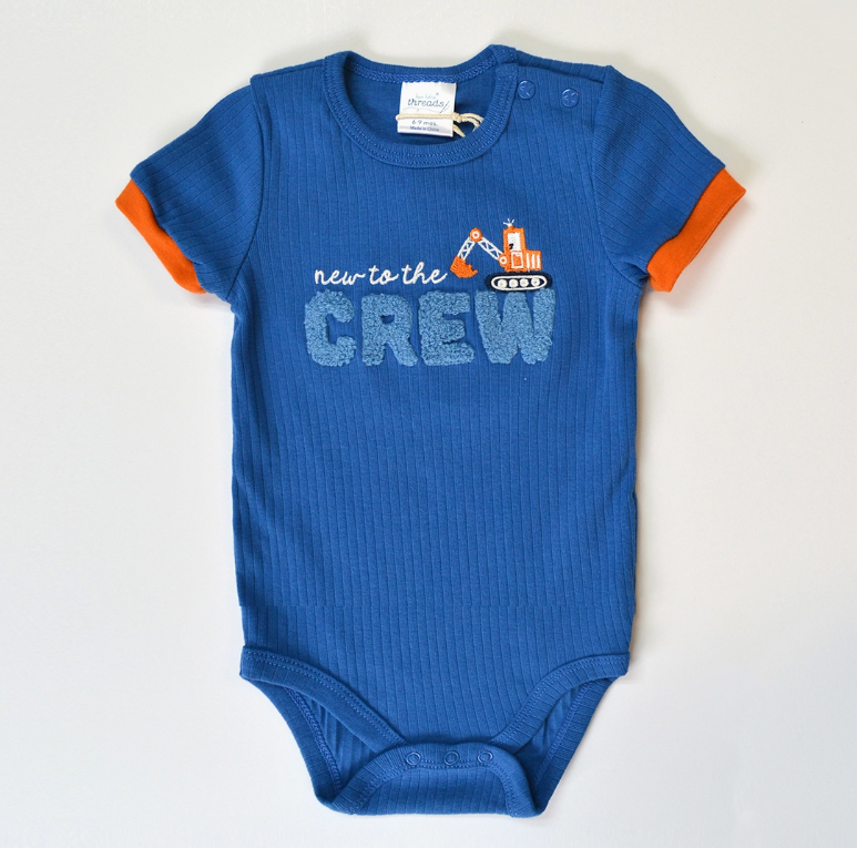 The Lollipop Dreams Tiny Crew Bubble Trio is a blue baby onesie with orange trim, decorated with a toy excavator and “new to the CREW” on the chest.