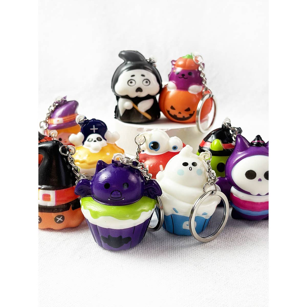 A collection of Love and Repeat Halloween Squishy Keychains, including ghosts, monsters, pumpkins, and cupcakes.