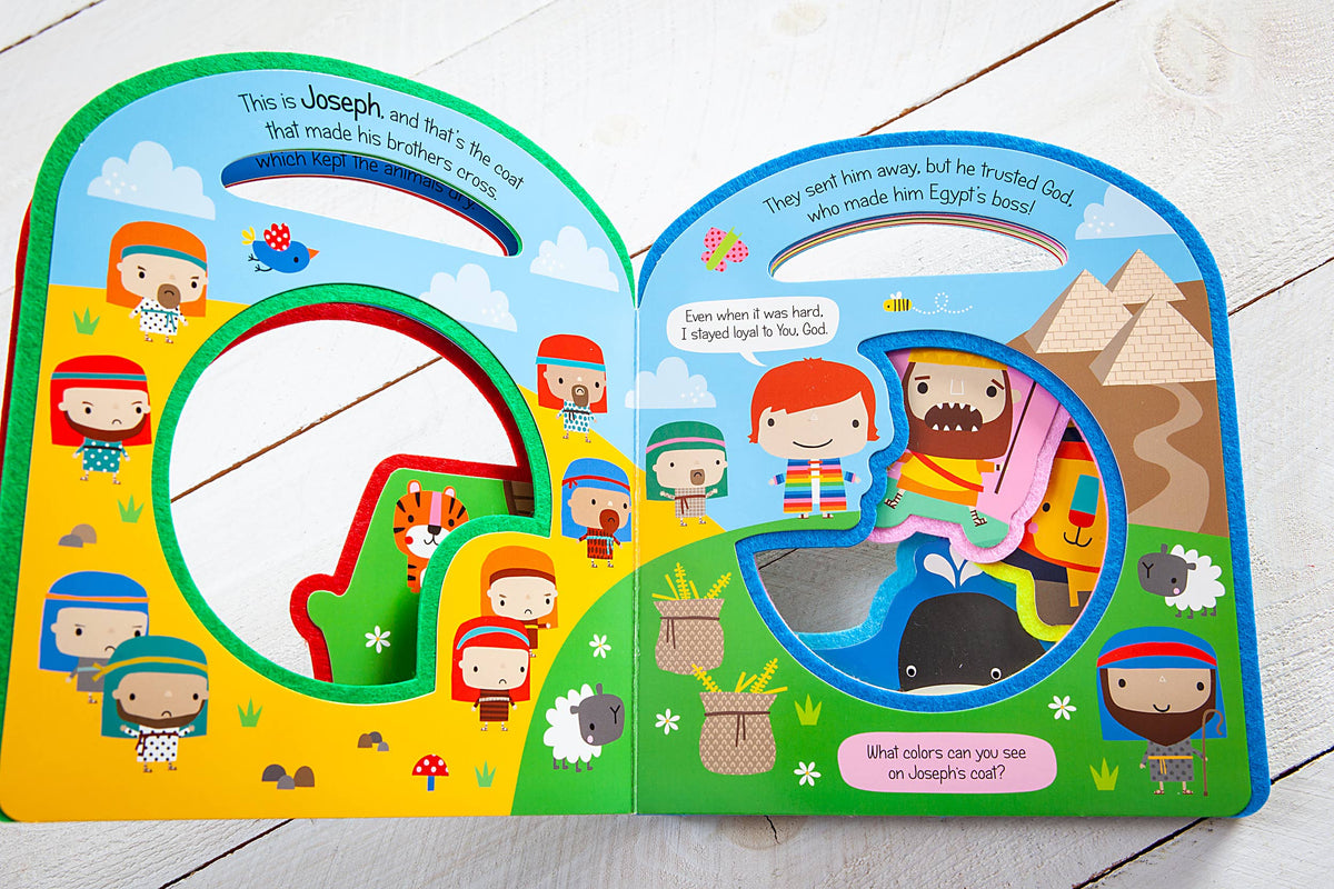 A vibrant Busy Windows Bible Stories Felt Book by BroadStreet Publishing Group, LLC is open to a Joseph scene, featuring cartoon characters, animals, and shapes. The page has a cut-out circle and poses a question about the colors on Joseph’s coat.