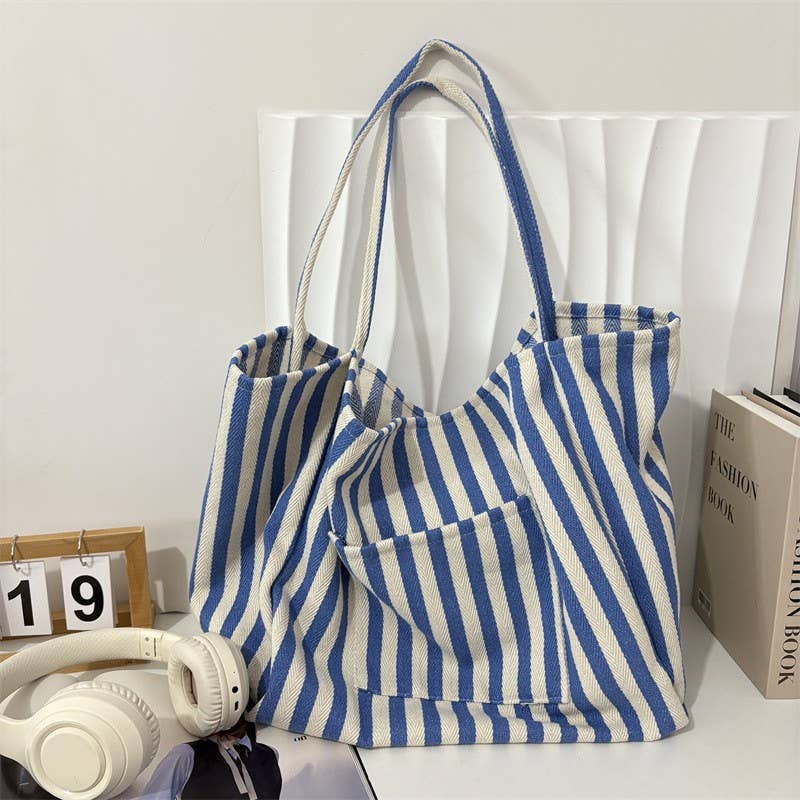 JOSSLYN by wall to wall Striped Blue Double Pocket Tote, a blue and white striped tote bag with two front pockets and long shoulder straps.