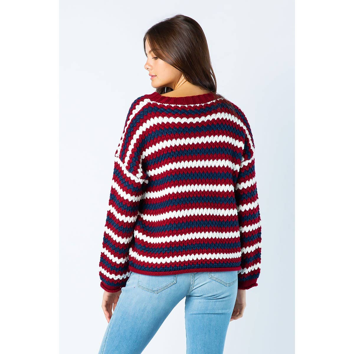 A person wearing a Sweet Generis Chunky Knit Multi Color Sweater featuring horizontal stripes in red, white, and dark blue.