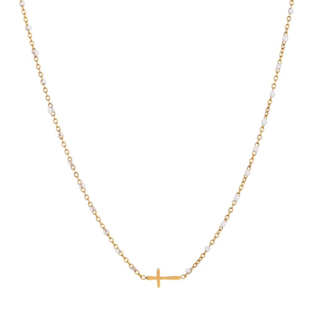 The JOSSLYN by wall to wall Dainty Cross Necklace features a delicate gold chain adorned with small white beads and a horizontal gold cross pendant at the center.