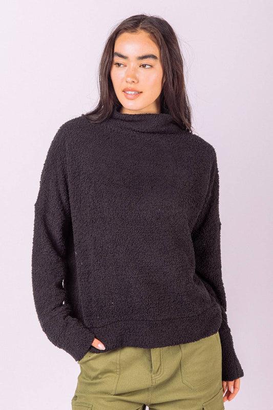 A person wears a black VERY J Fuzzy Textured Solid Knit Top, featuring a long-sleeved, fuzzy, textured knit finish and a mock neckline.