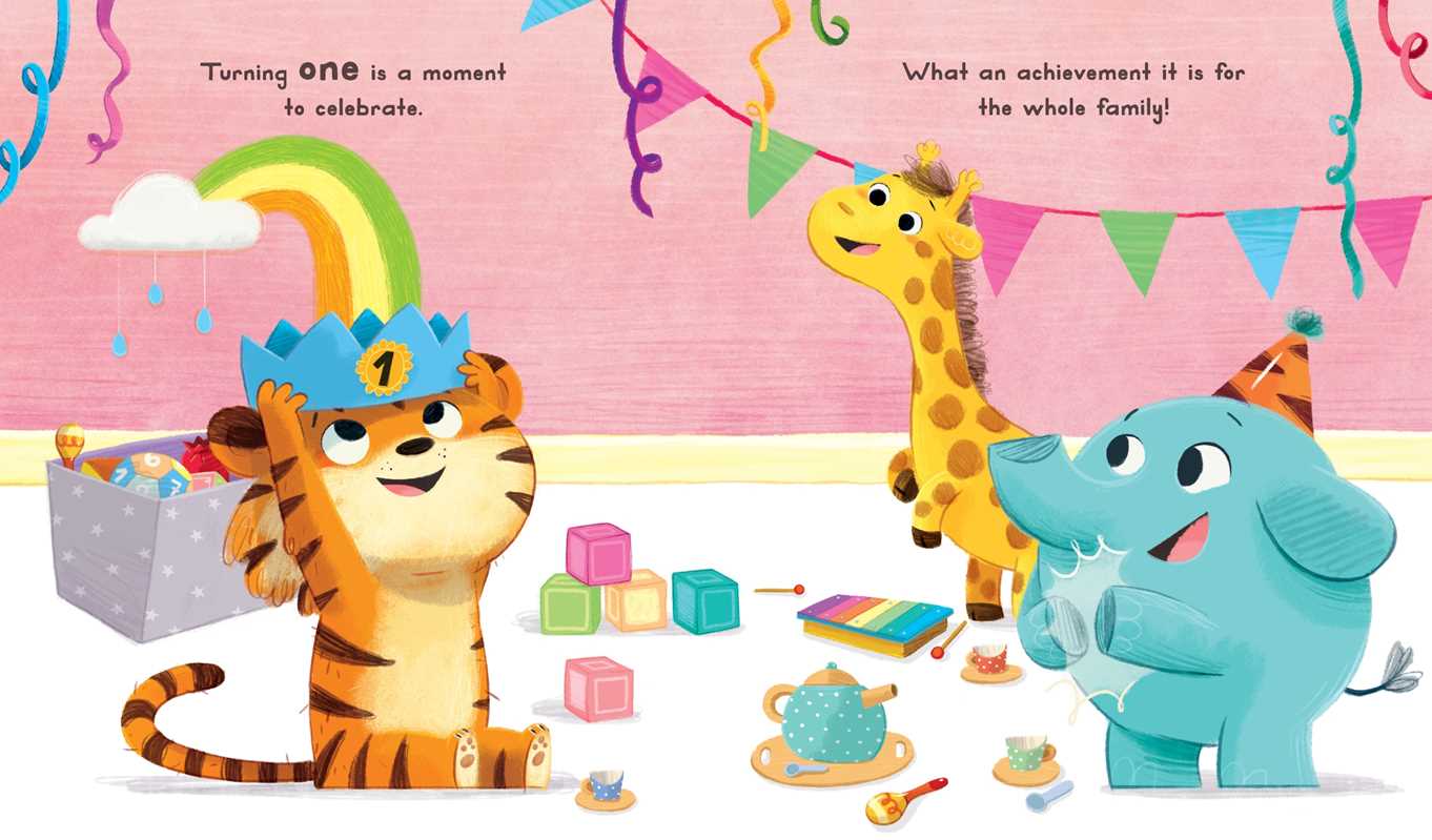 The Now You Are 1 Book by Simon & Schuster features an illustrated tiger cub wearing a crown, celebrating a first birthday with an elephant and giraffe among colorful decorations, toys, and a rainbow. "Now You Are 1" appears at the top.