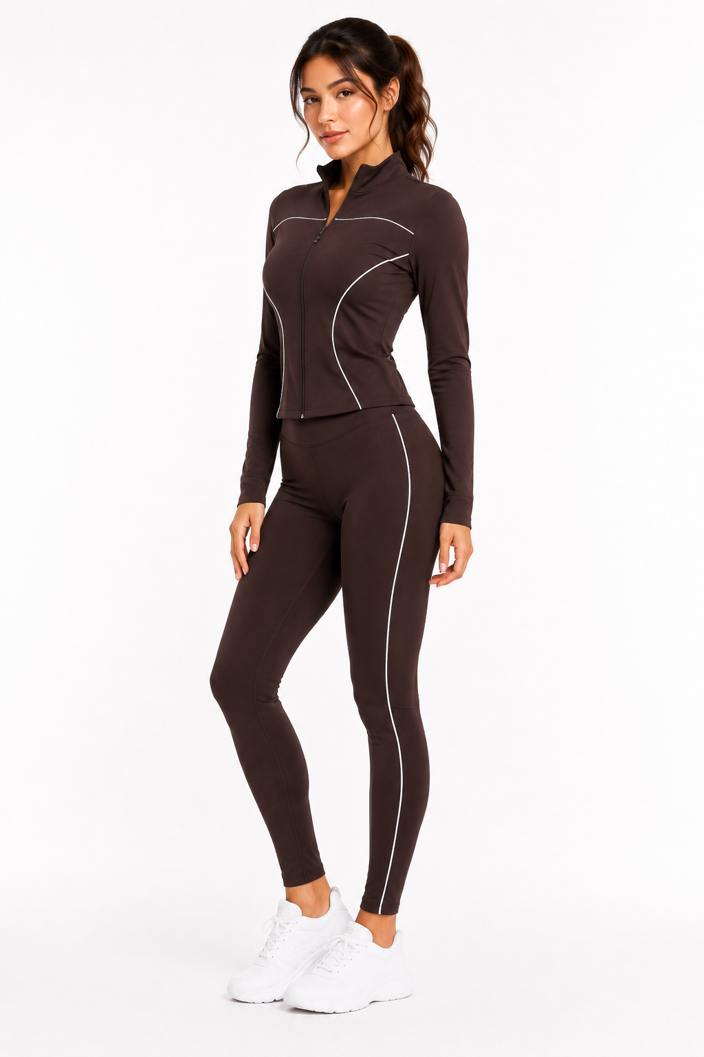 A woman wearing the Color 5 Chocolate Brown Active Set—featuring a fitted athletic jacket and matching leggings with white piping—paired with white sneakers, stands against a plain white background.